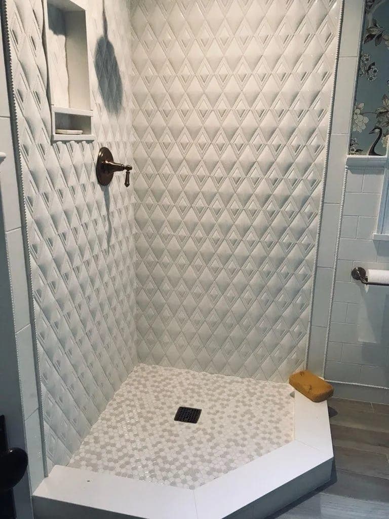 Corner shower with white diamond-pattern tile and a mosaic floor by Palm Beach Renovations