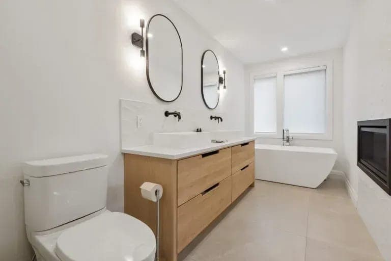 Modern bathroom with a floating wood vanity and freestanding tub by Palm Beach Renovations