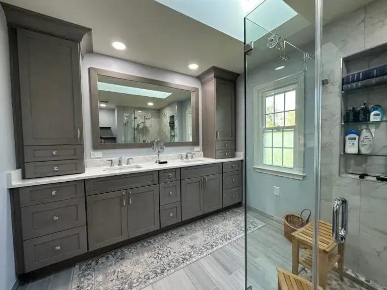 Master bathroom with a gray double vanity and glass shower by Palm Beach Renovations