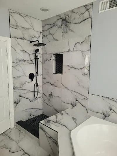 Marble bathroom with a rainfall shower and soaking tub by Palm Beach Renovations