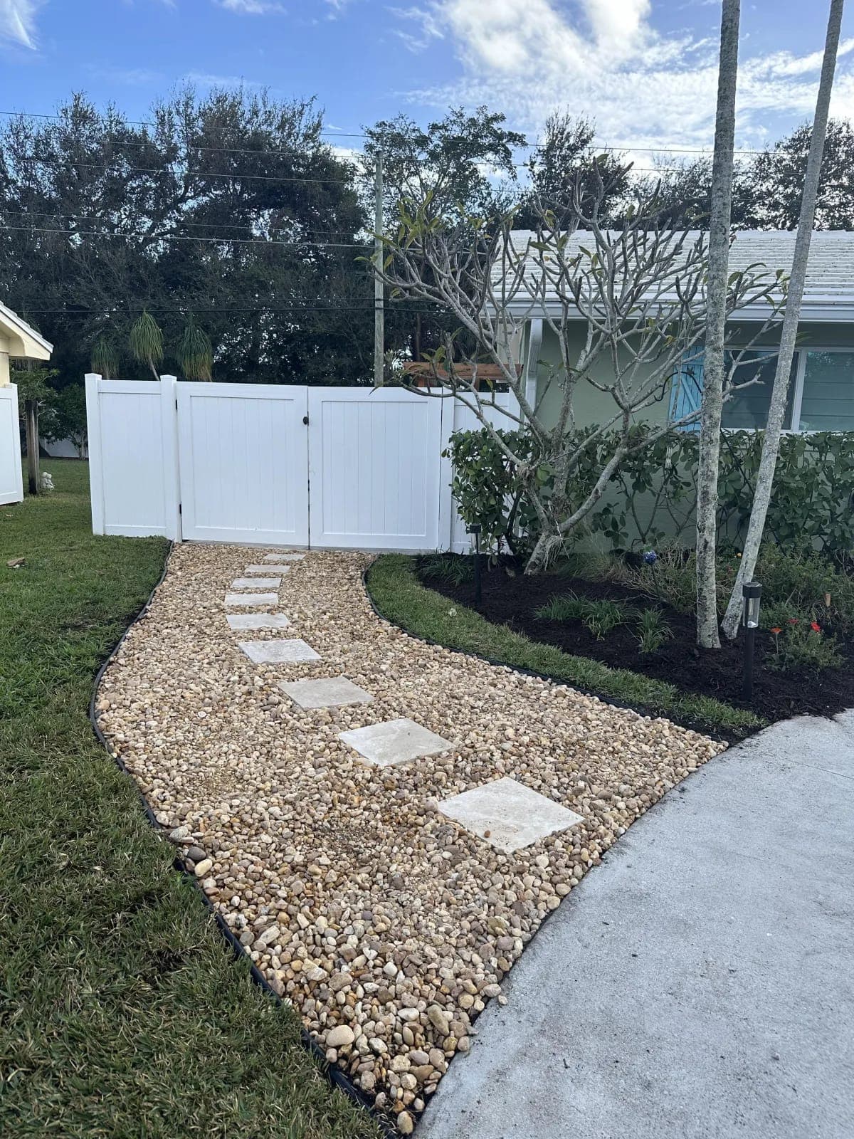Paver stepping-stone walkway set in river rock by Palm Beach Renovations