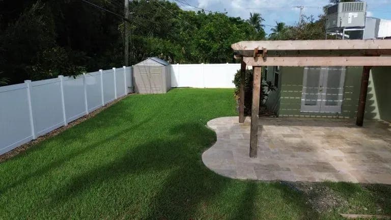 Travertine paver patio with a wood pergola by Palm Beach Renovations